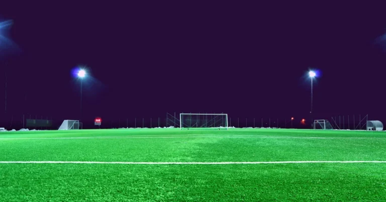Campo de fútbol con el césped iluminado por focos de noche