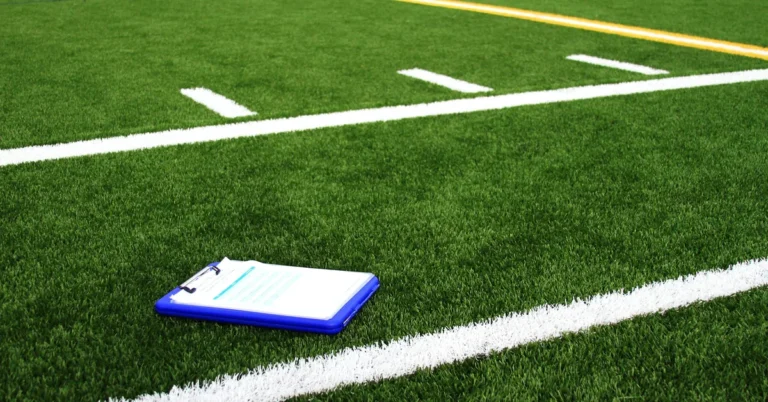 Portapapeles con hojas de jugadas sobre el césped de un campo de fútbol americano